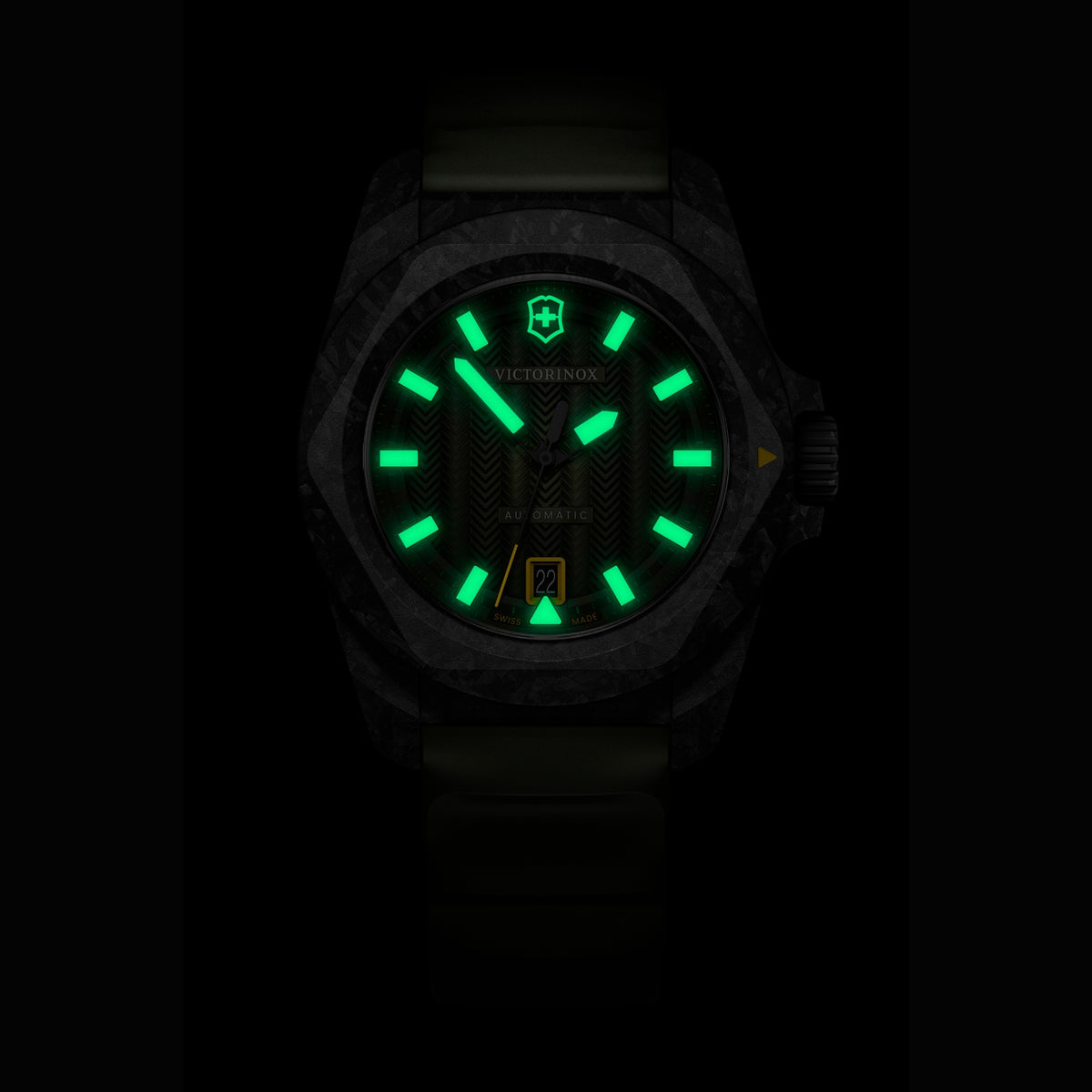 Close-up of a Victorinox automatic watch at night, featuring green glowing lume