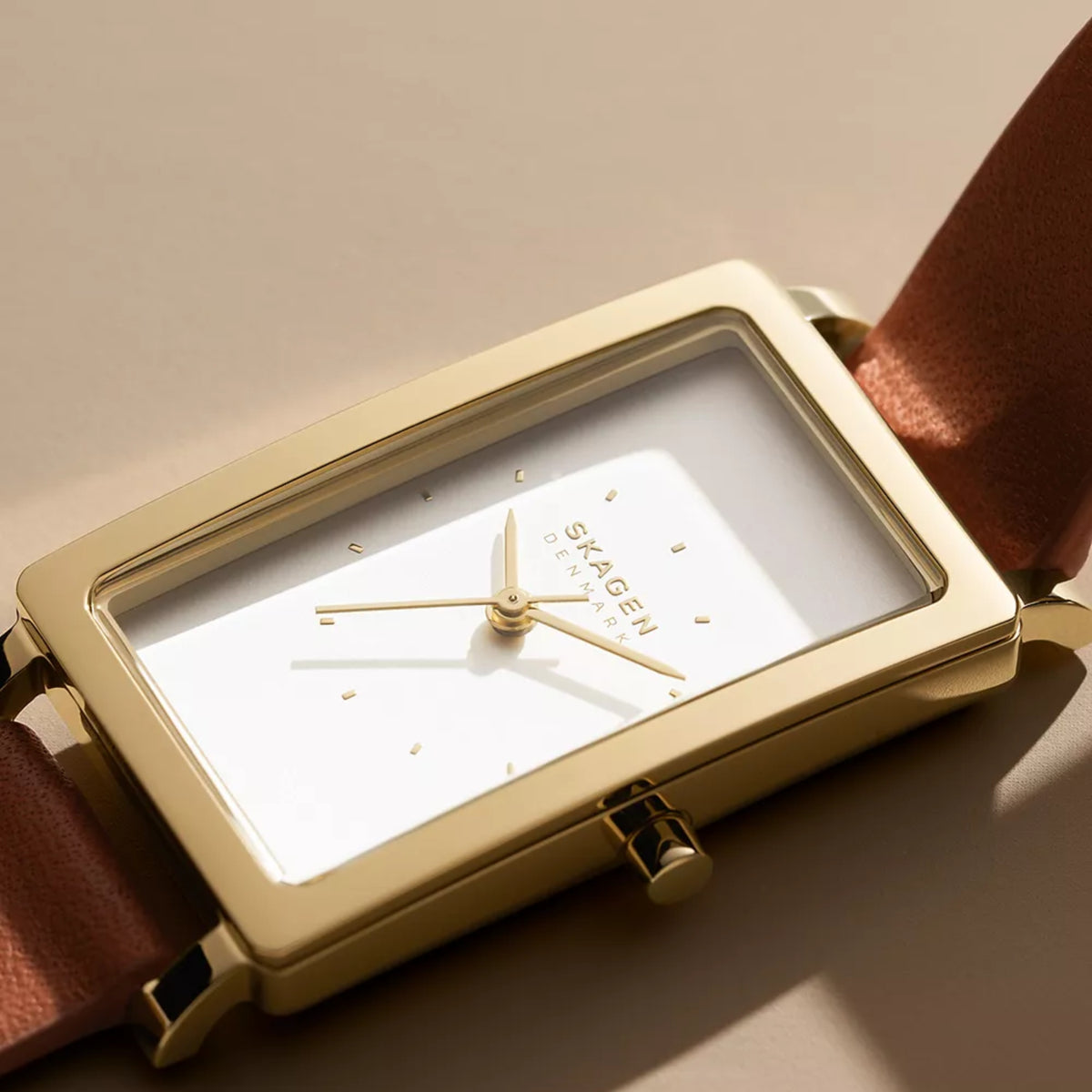 Close-up of white dial rectangular watch with gold-tone bezel and crown