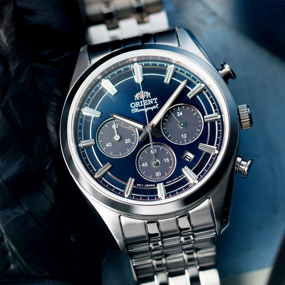 Steel chronograph solar watch with navy dial and linked bracelet, angled view