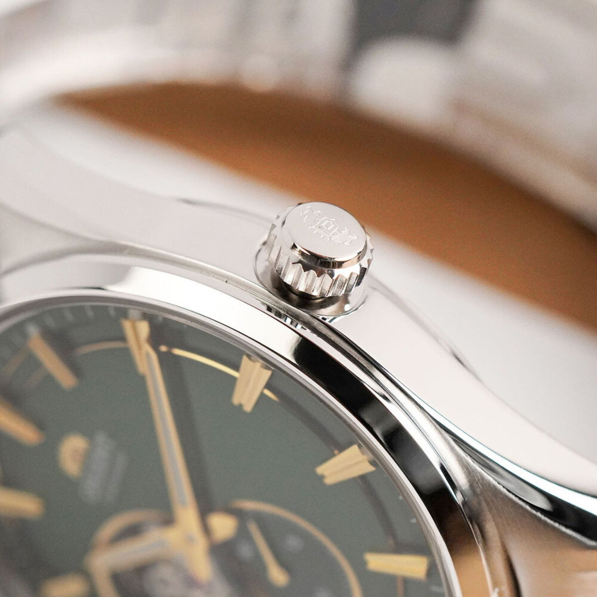 Close-up view of the polished bezel edge and textured crown engraved with the brand logo on the Orient Semi Skeleton RA-AR0008E30B