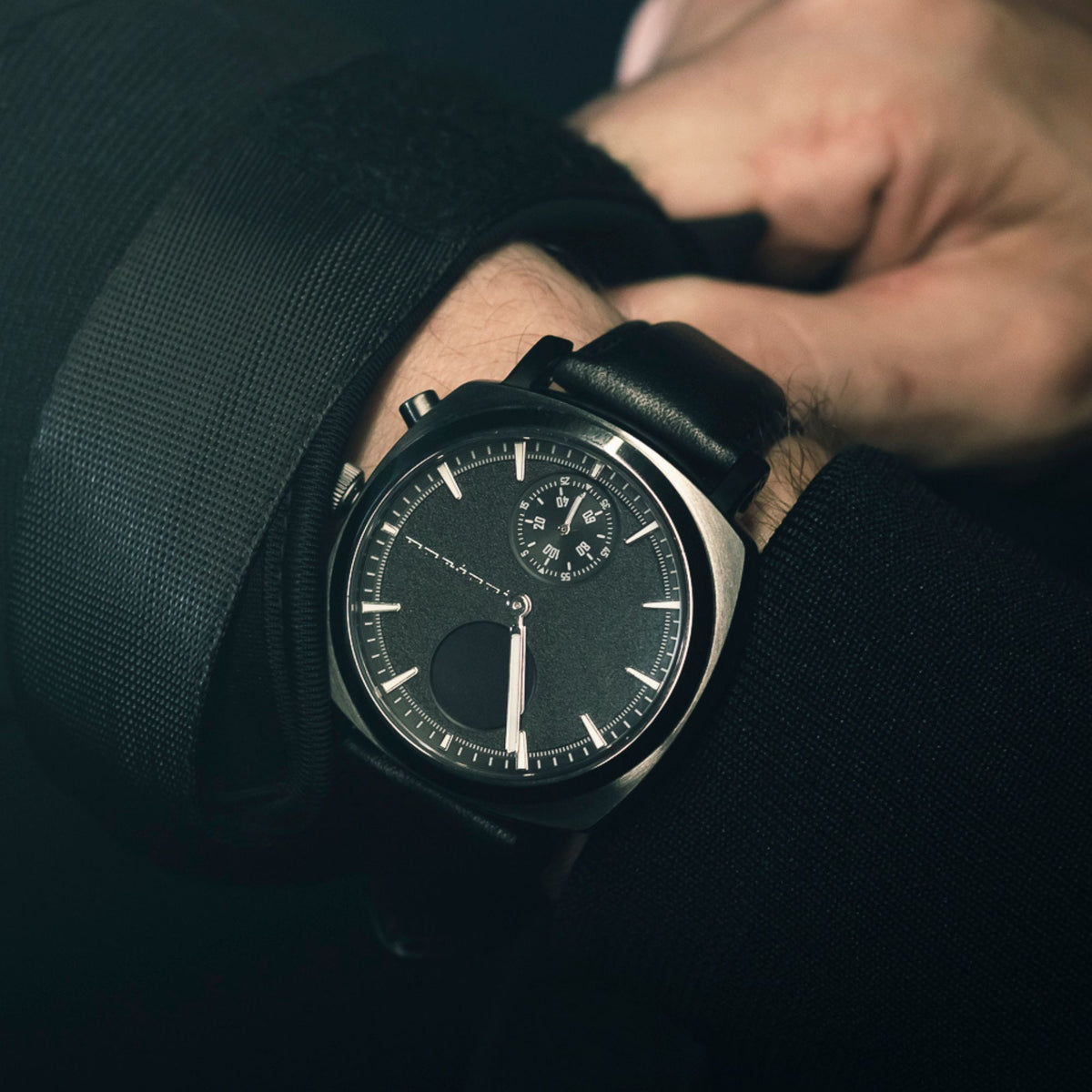 Hybrid smart watch on sleeve with black leather strap and dark slate dial