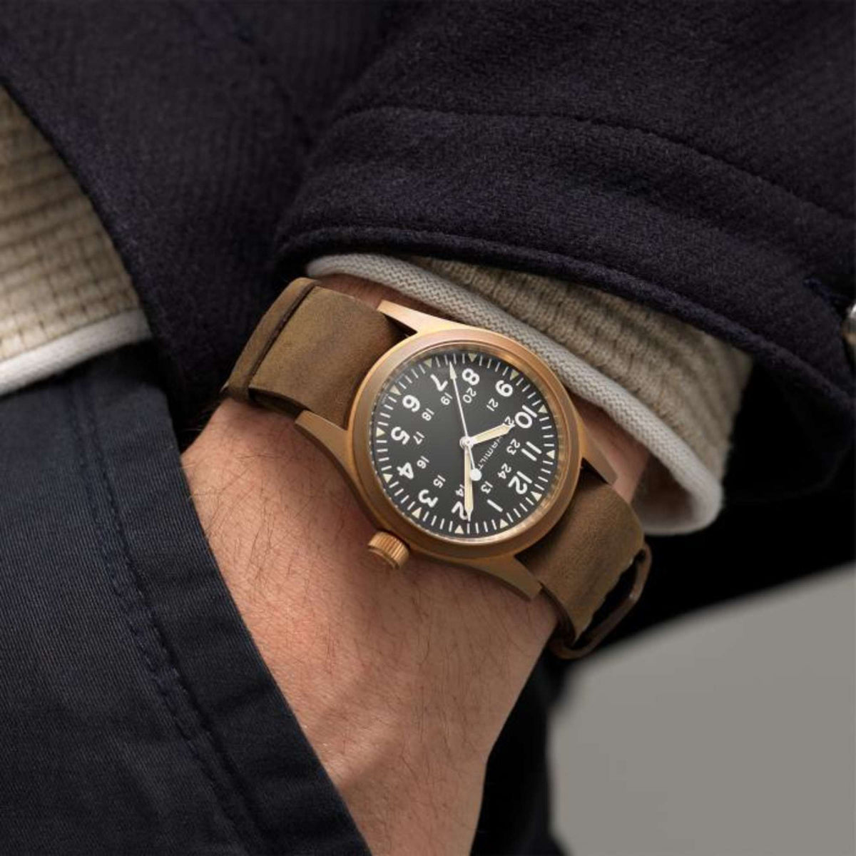 Hamilton Khaki Field H69459530 wrist shot showing hand-wound wristwatch with bronze case, black dial, and brown leather band