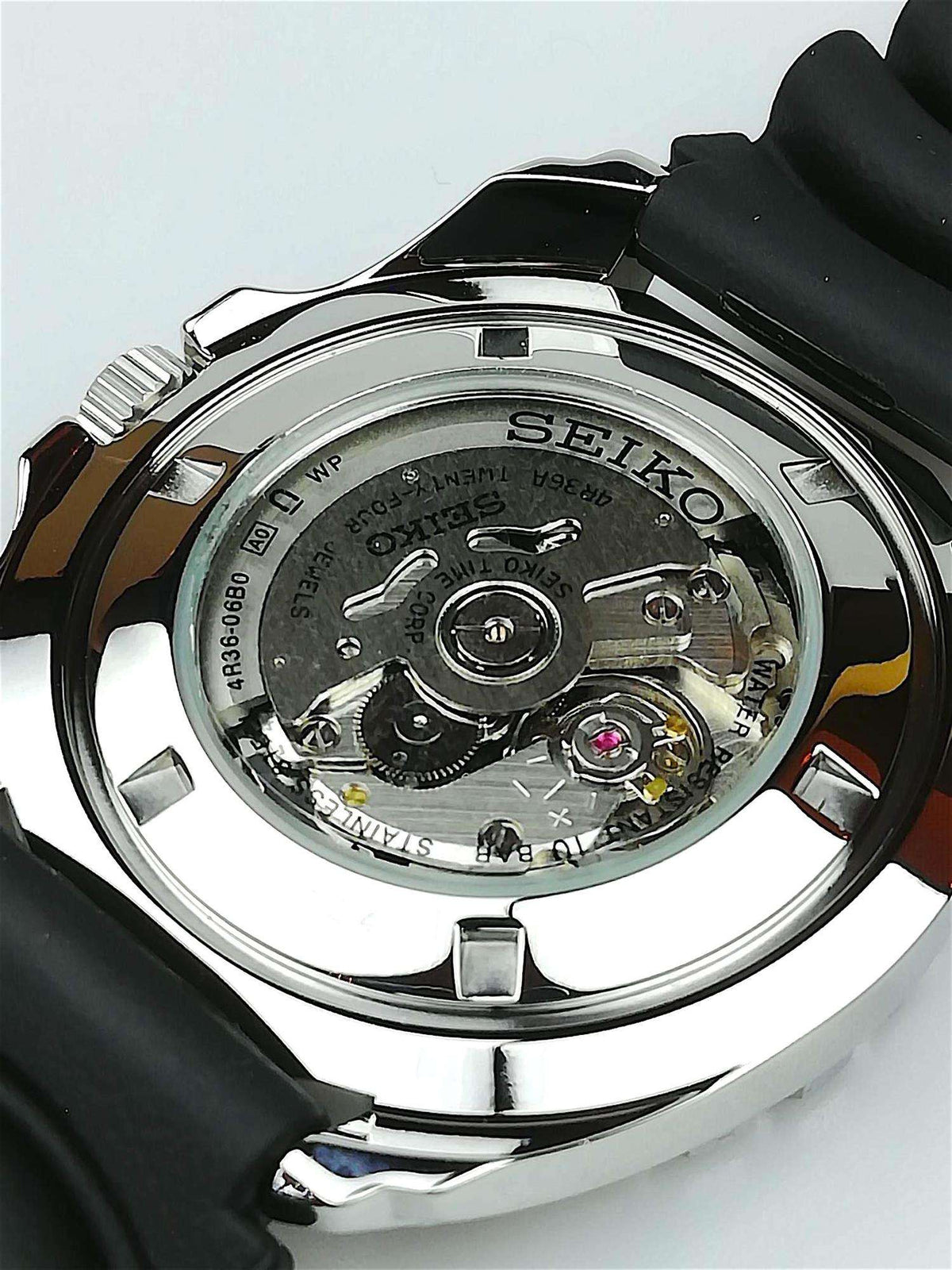 Stainless steel watch caseback showing mechanical movement under clear cover