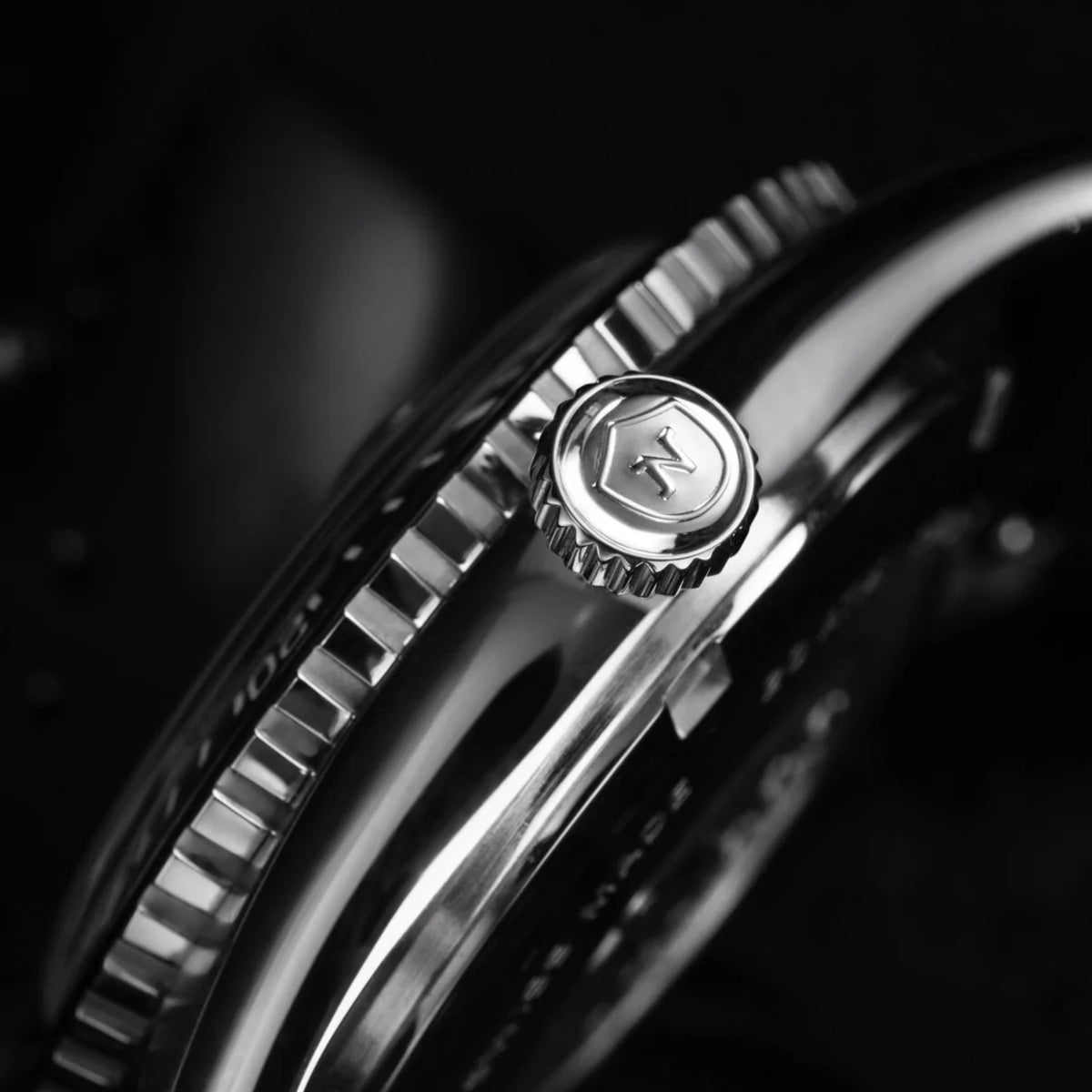 Side view of stainless steel diver watch crown and bezel teeth in black and silver