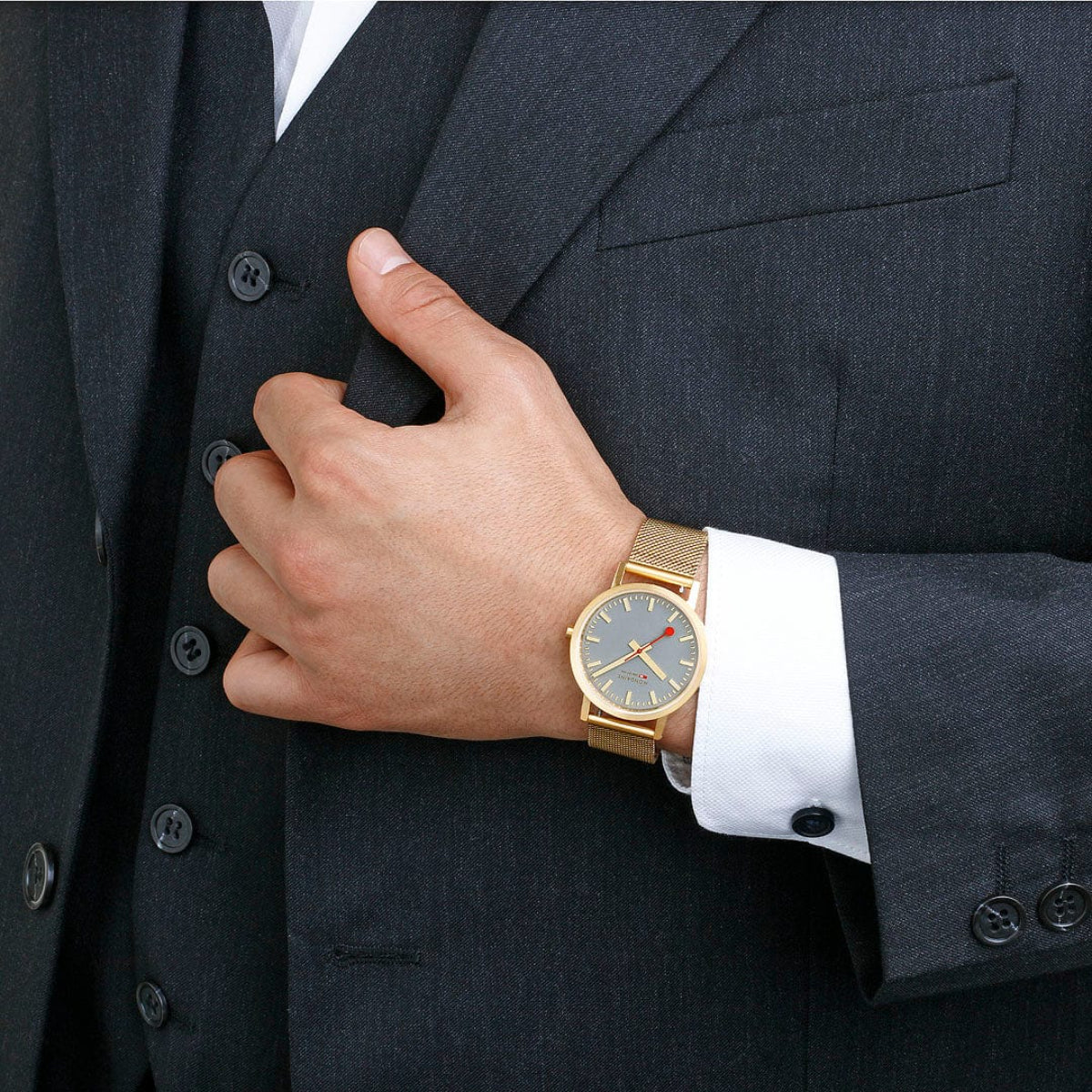 Quartz watch on wrist, gold-tone mesh strap, gray dial with red seconds