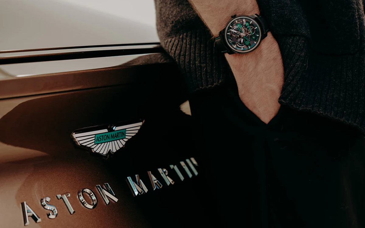 Close-up of premium Aston Martin automatic skeleton timepiece and rear car emblem
