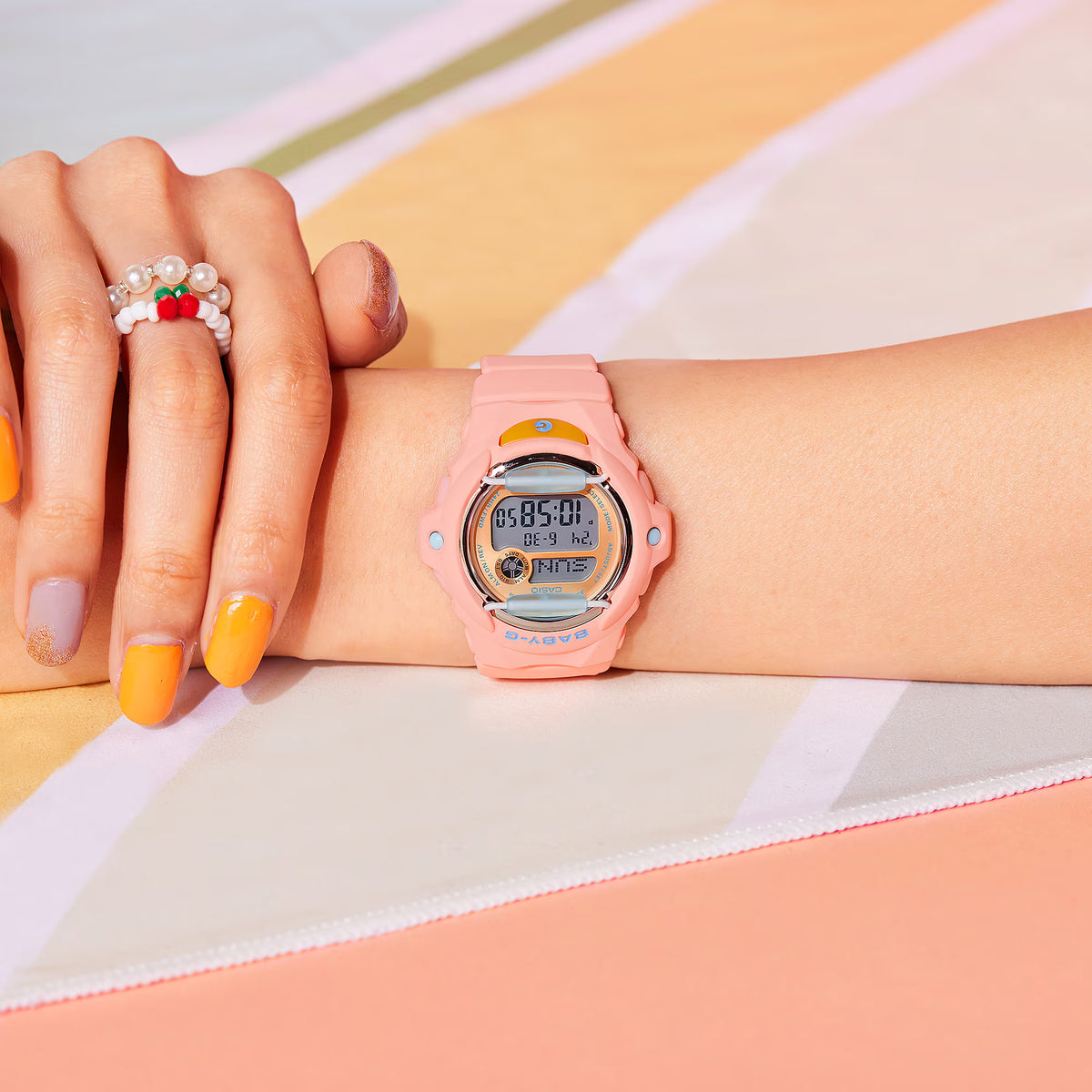 On-wrist view of the Casio Baby-G BG-169PB-4ER watch showcasing its pink resin strap and orange dial accent