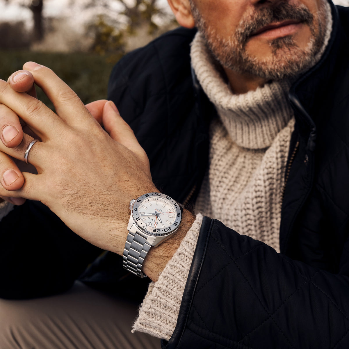 Men's steel bracelet watch with white dial and date window, worn on wrist