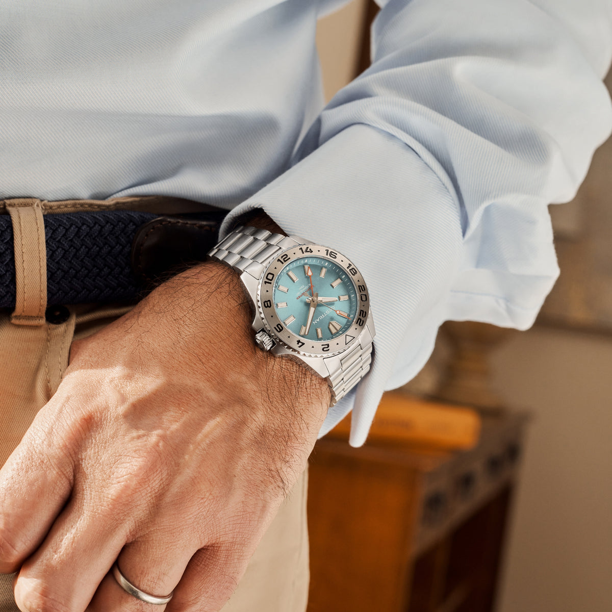 Men's automatic GMT watch wrist close-up, steel bracelet with blue dial details