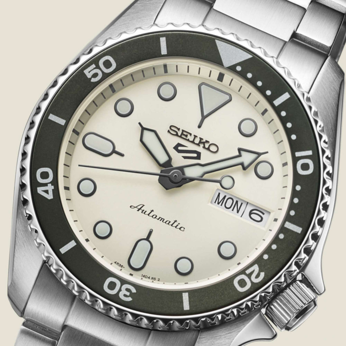 Seiko watch dial close-up with cream face, black bezel ring, MON 6, and automatic