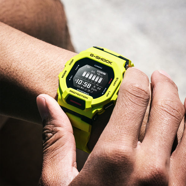 Neon green G-Shock watch on wrist with LCD showing 10:58