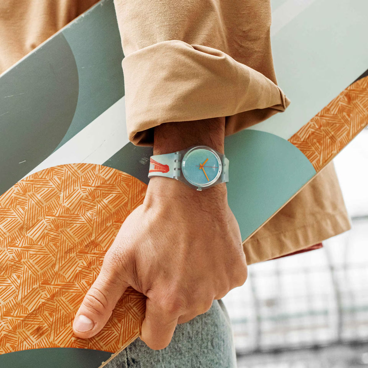 Swatch quartz watch close-up: light blue case, orange hands, textured strap pattern