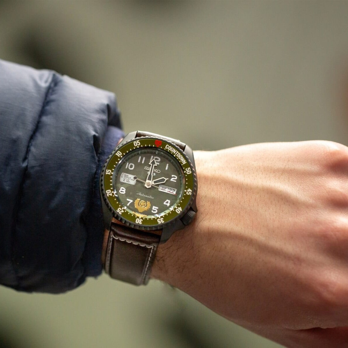 Men's Seiko watch on wrist with dark dial, colorful accents, and tan leather strap
