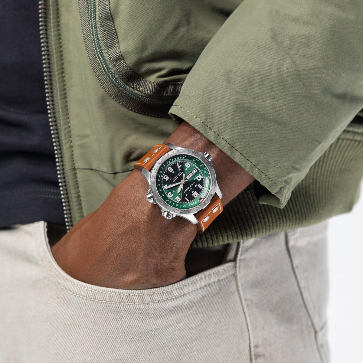 Hamilton Khaki Aviation H77735560 pilot watch wrist shot styled with green jacket highlighting green dial and brown leather strap