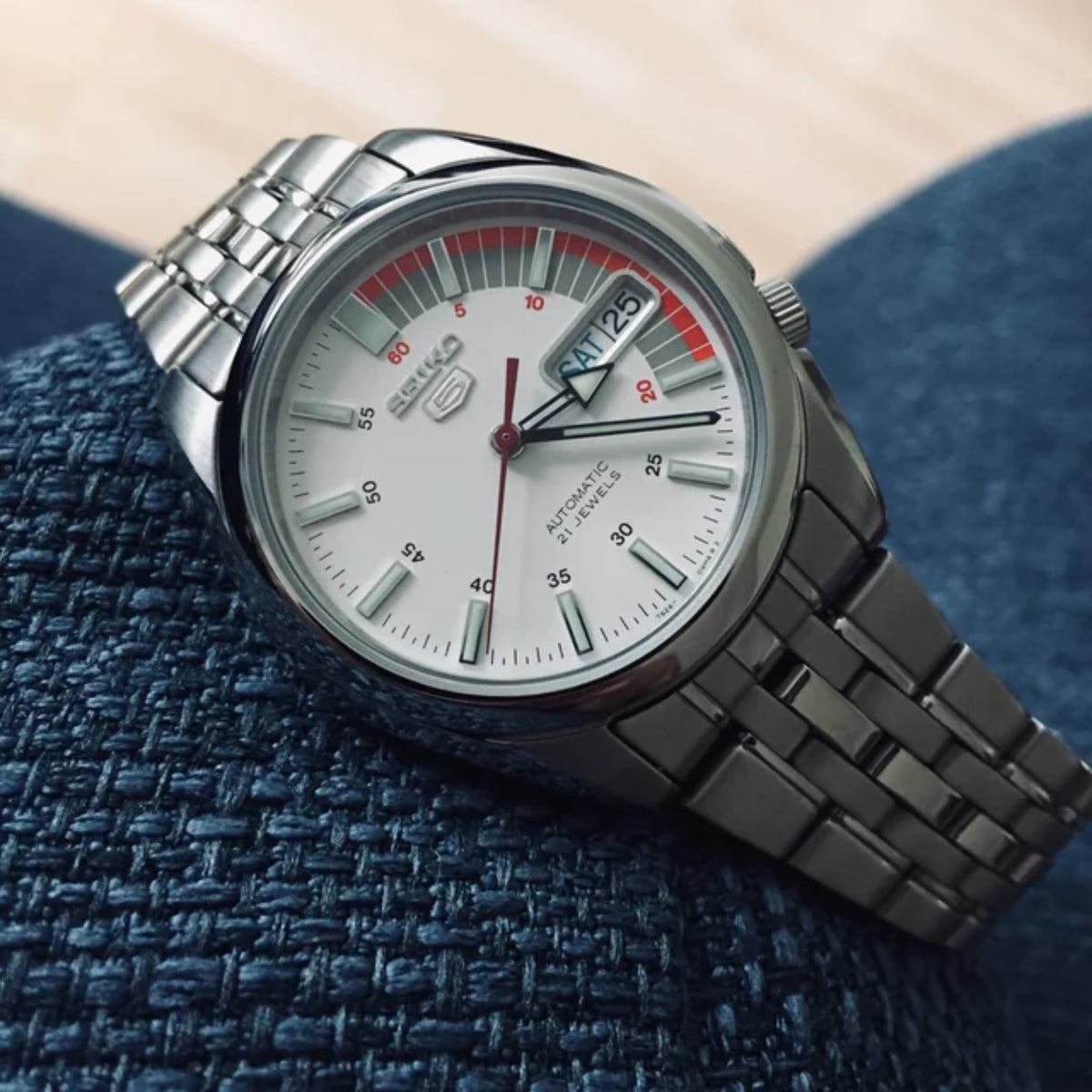 Seiko 5 Automatic SNK369K1 highlighting the white dial layout, red accents, and multi-link steel bracelet