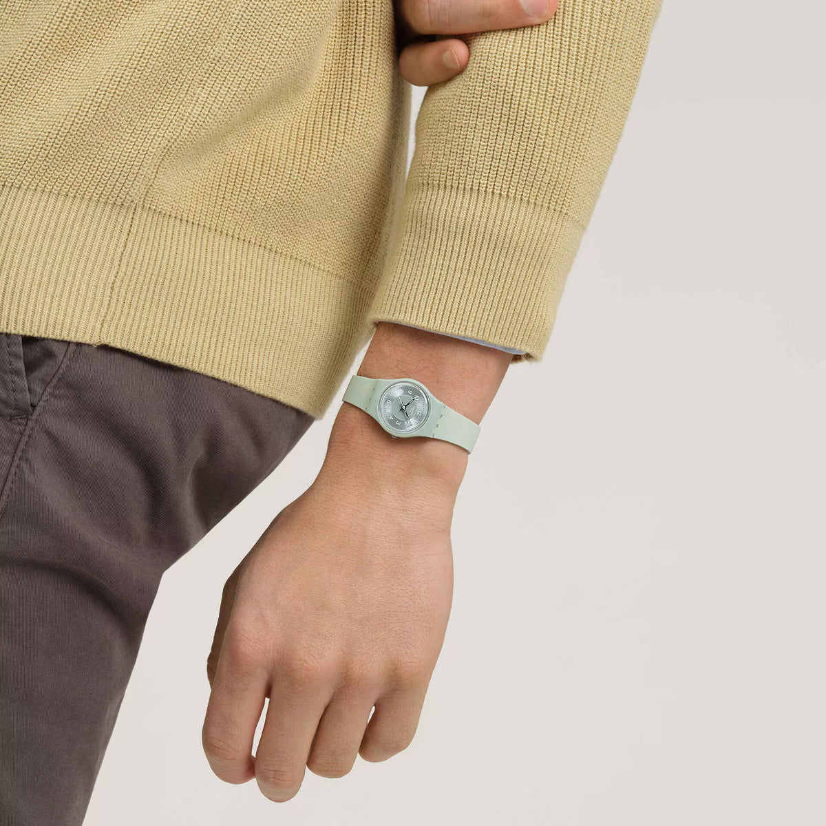 Swatch sage green silicone strap watch on wrist with round dial and bezel