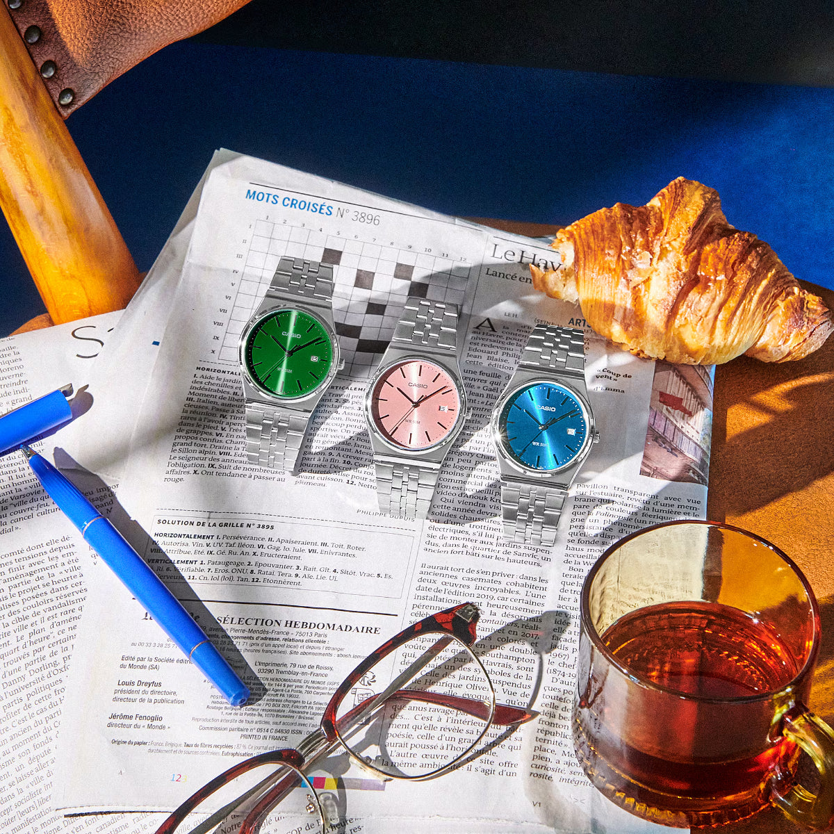Casio MTP Collection MTP-B145D-2A2VEF blue dial watch positioned alongside green and pink dial variants on a newspaper