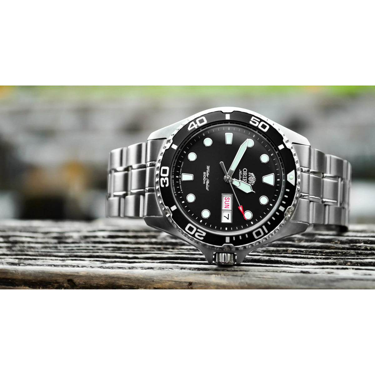 Men’s automatic dive watch on wood with black dial, bezel numbers, and date window