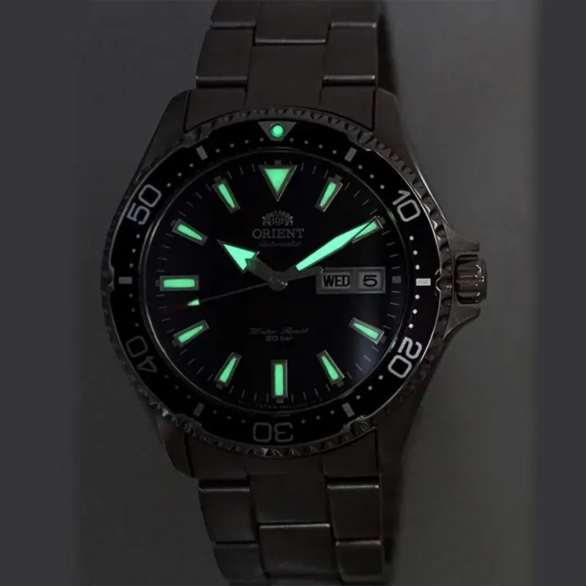 Glowing green luminous hands and markers on an Orient Mako watch dial in the dark