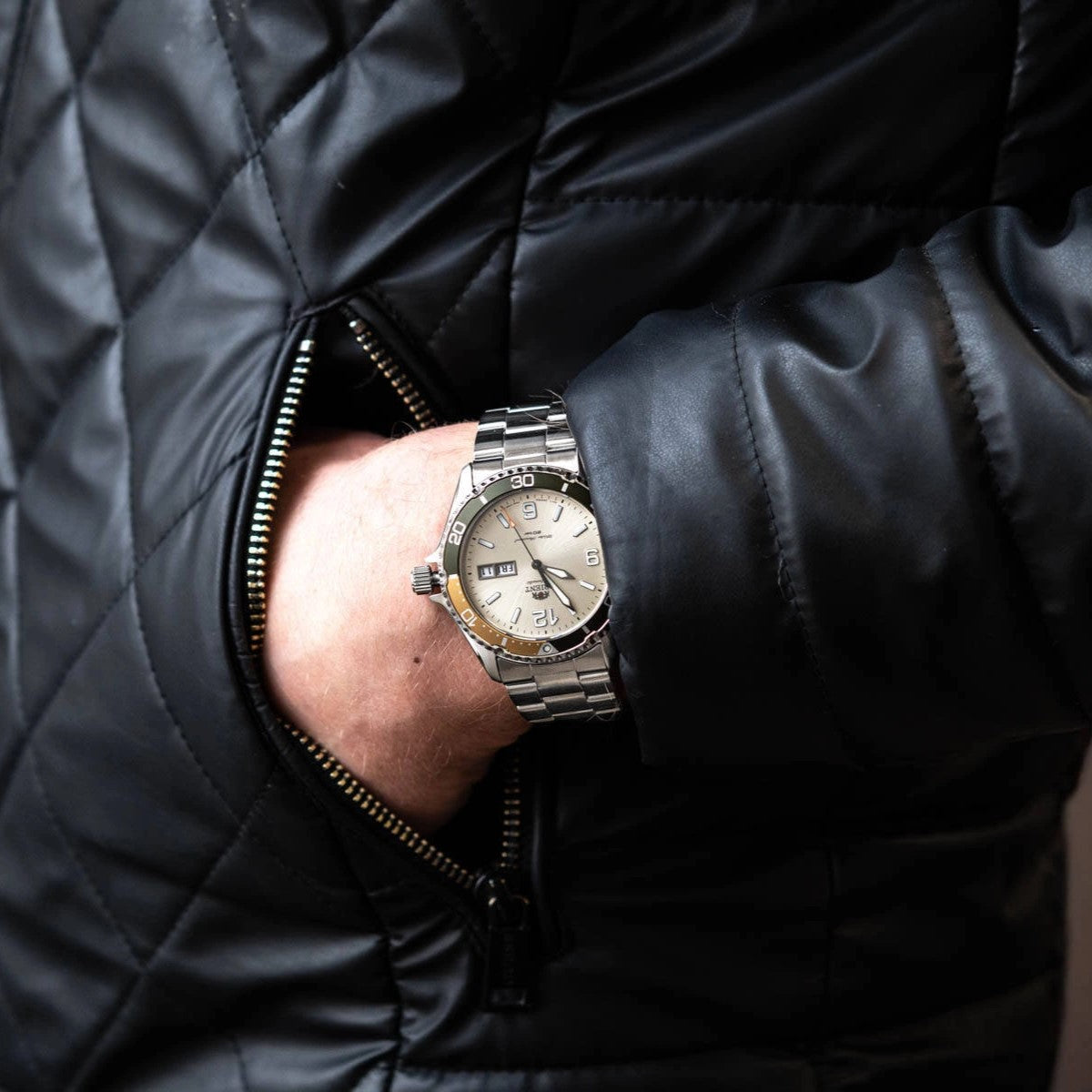 Men's automatic steel watch on wrist with beige-toned dial and metal bracelet