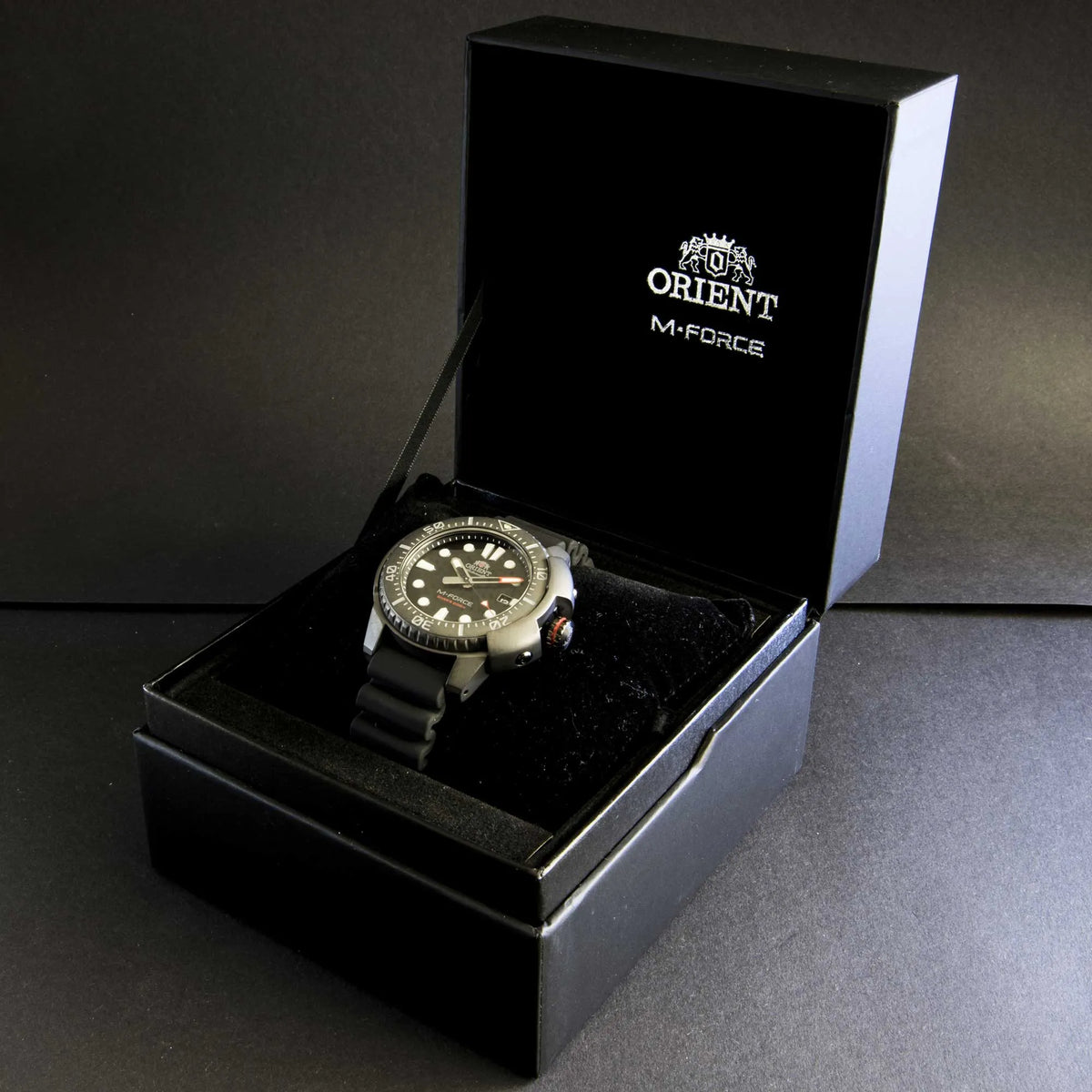 Orient M-Force watch resting in open gift box with brand logo on the lid
