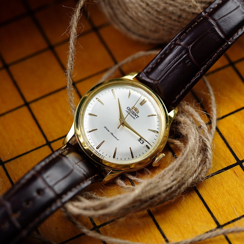 Orient classic gold-tone automatic dress watch with a white dial, date window, and dark brown leather strap