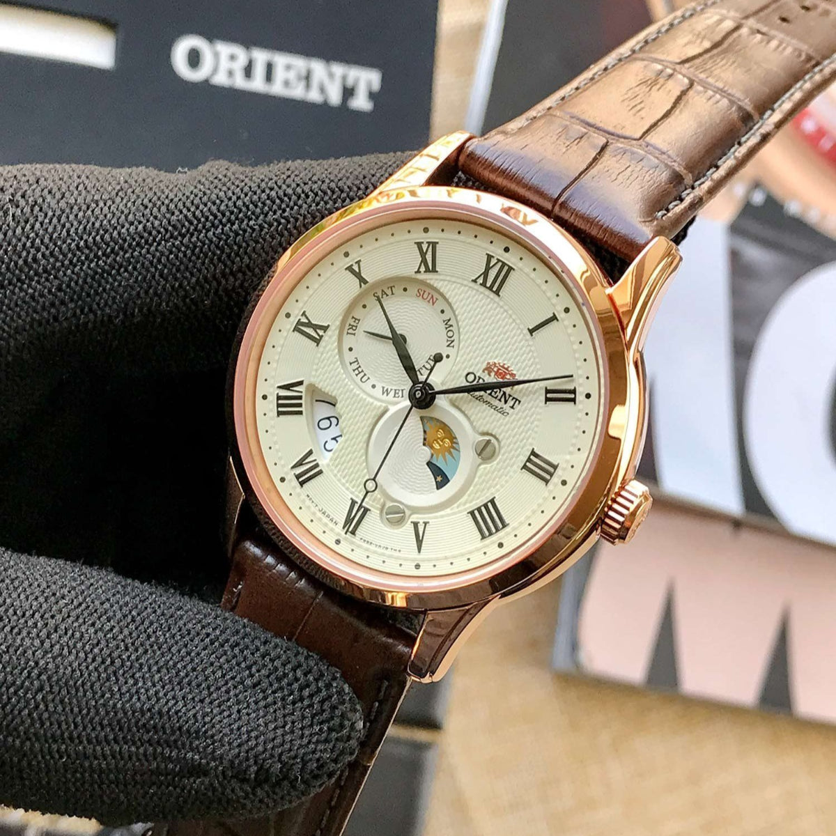 Side view of Orient Bambino Sun & Moon RA-AK0007S30B mens watch held in hand against background