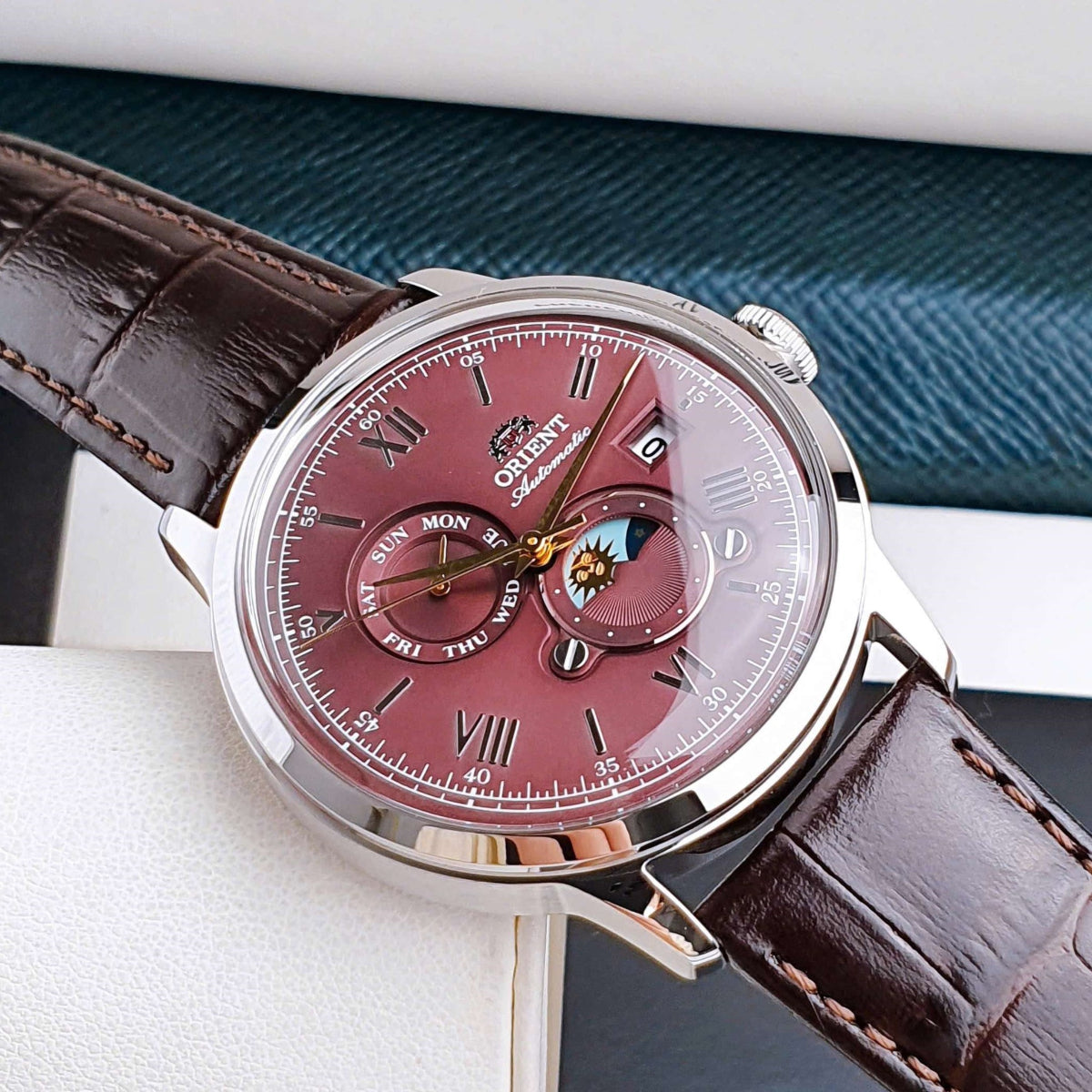 Angle view highlighting the red dial and stainless steel case of the Orient Bambino RA-AK0807R30B mens automatic watch