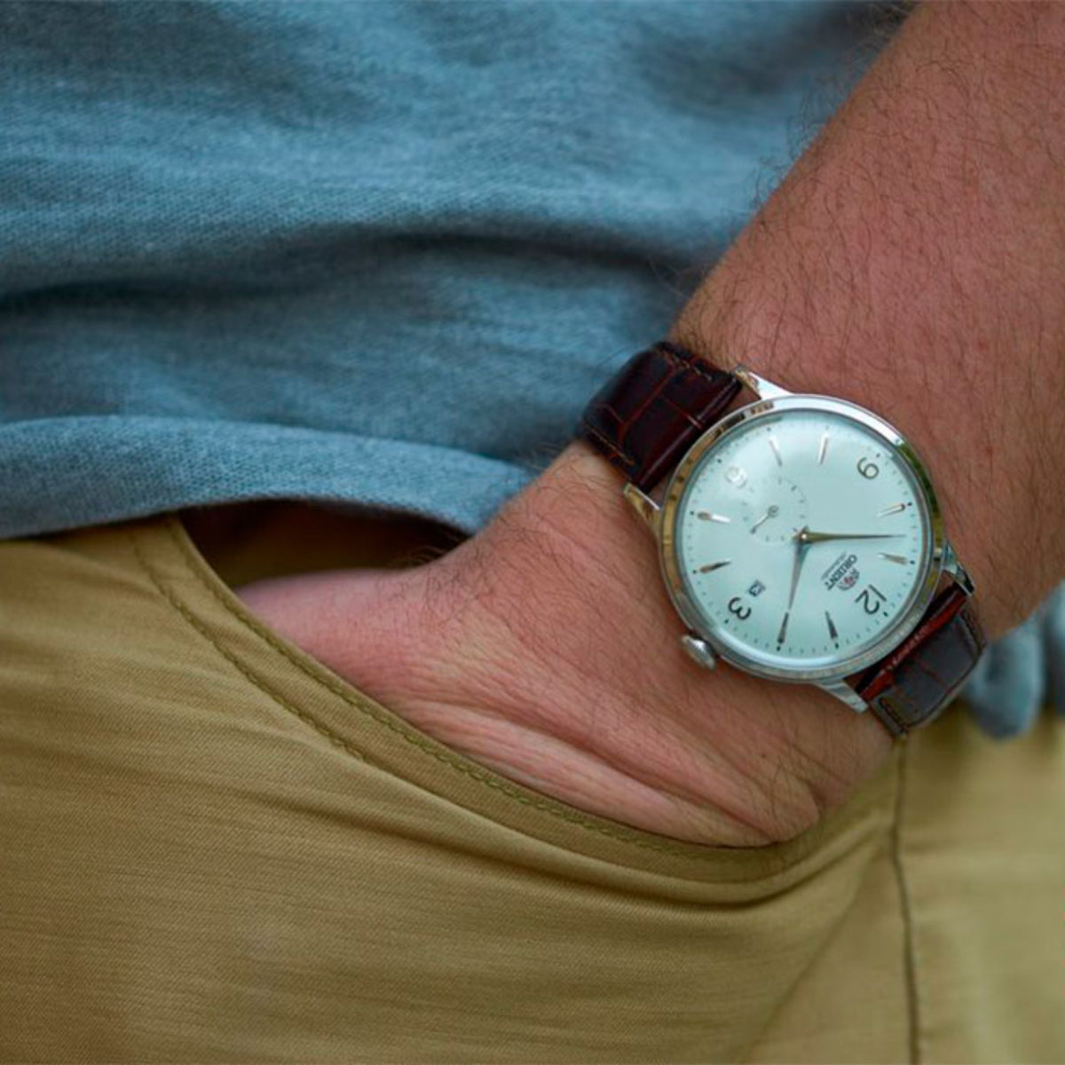 Men's wristwatch with brown leather strap and white dial on a forearm