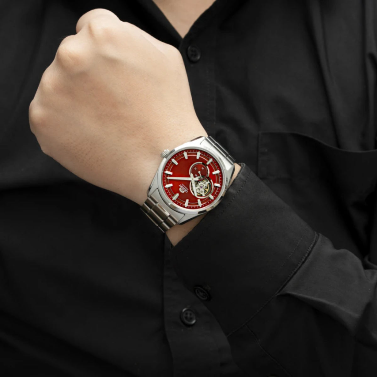 Men’s steel automatic watch on wrist with red open-heart dial