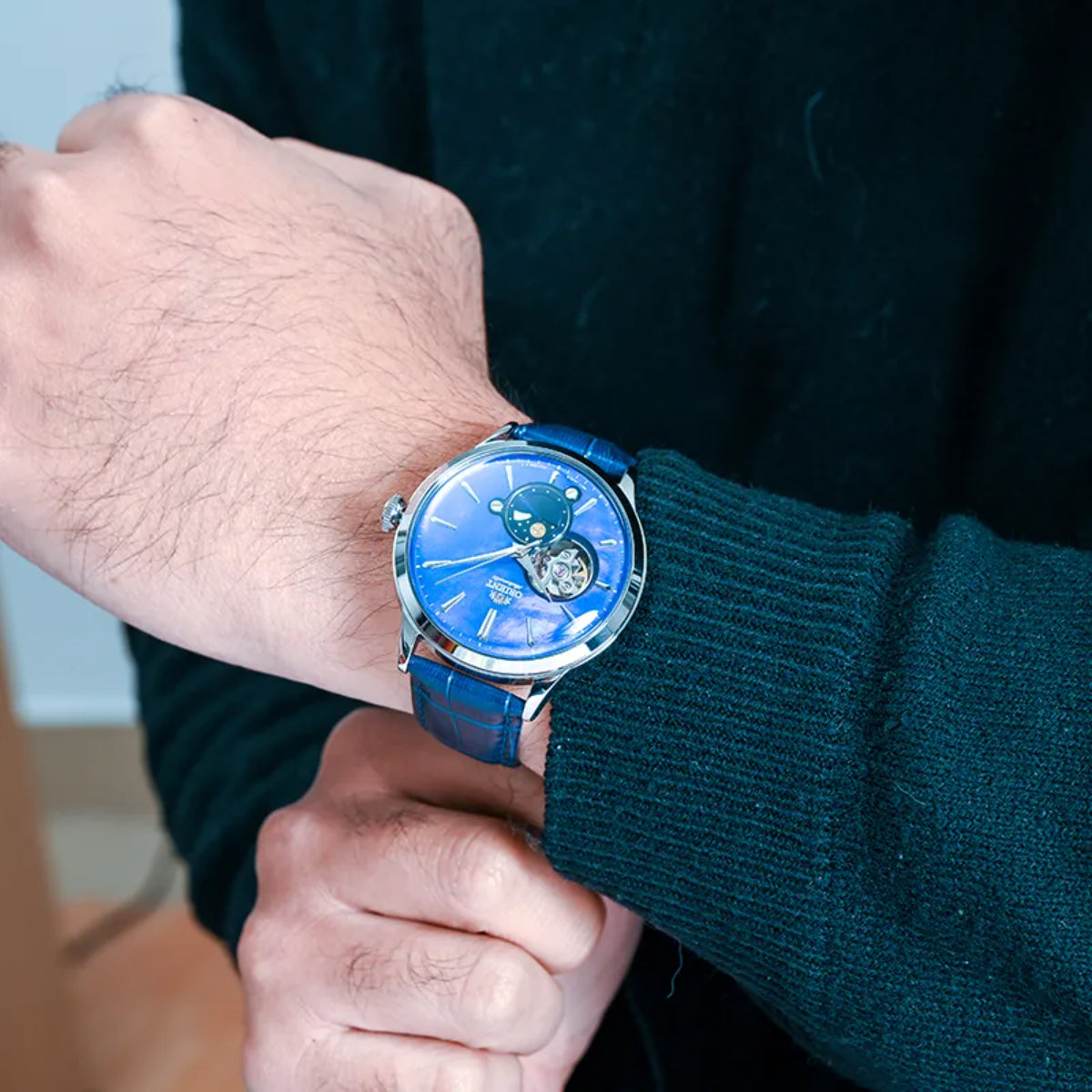 Men's automatic wristwatch on wrist with blue dial and blue leather strap