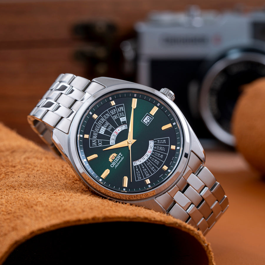 Orient multi-year calendar automatic watch featuring an emerald green dial, gold hour markers, and stainless steel bracelet