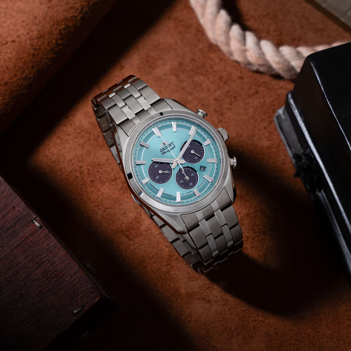Solar chronograph wristwatch with light blue dial and steel link bracelet.