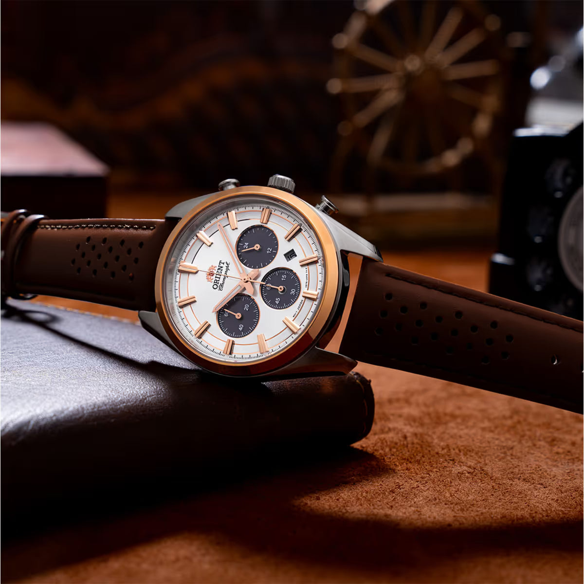 Solar chronograph watch with white dial and brown leather strap resting on surface
