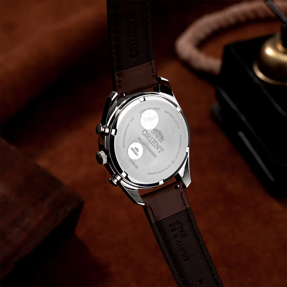Caseback of solar chronograph watch with brown leather strap and silver hardware
