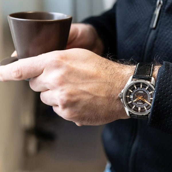 Men's automatic watch worn on wrist with black dial and black leather strap.