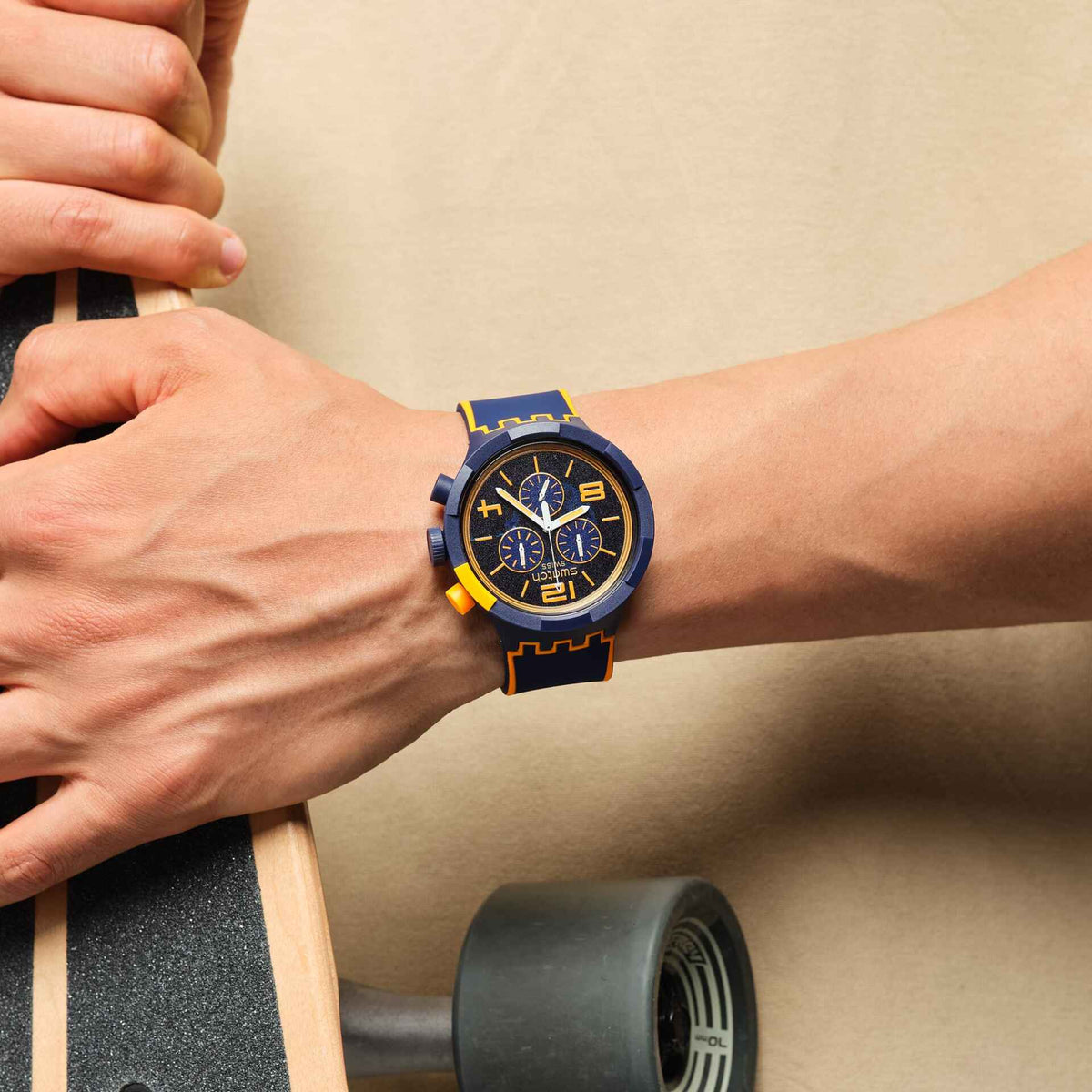 Men's wristwatch on arm, blue silicone strap with orange accents and blue chronograph dial
