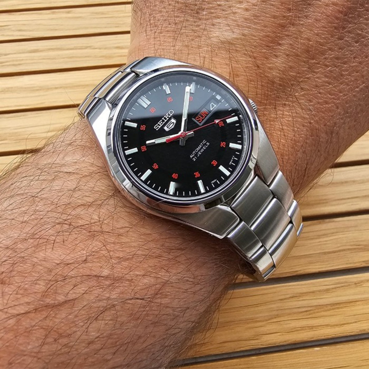 Seiko 5 automatic black dial stainless steel bracelet watch on wrist