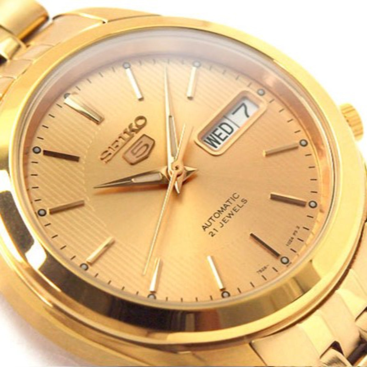 Close-up of gold Seiko 5 watch dial with day/date window and automatic 21 jewels text.