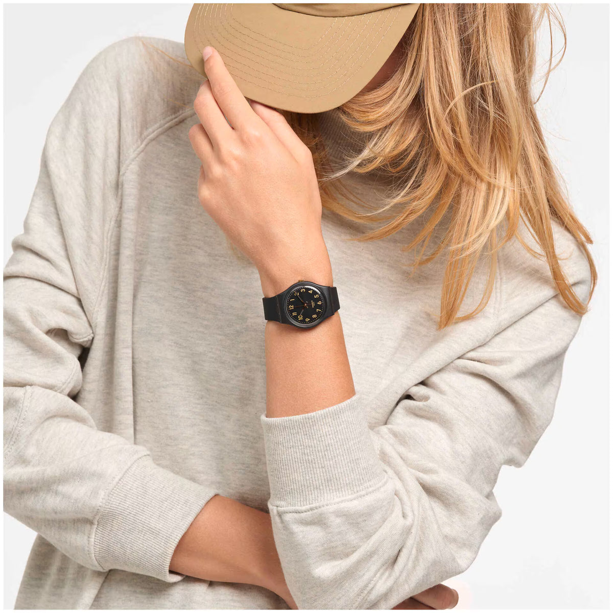 Swatch black watch on wrist with black dial, gold hands, and dark silicone strap