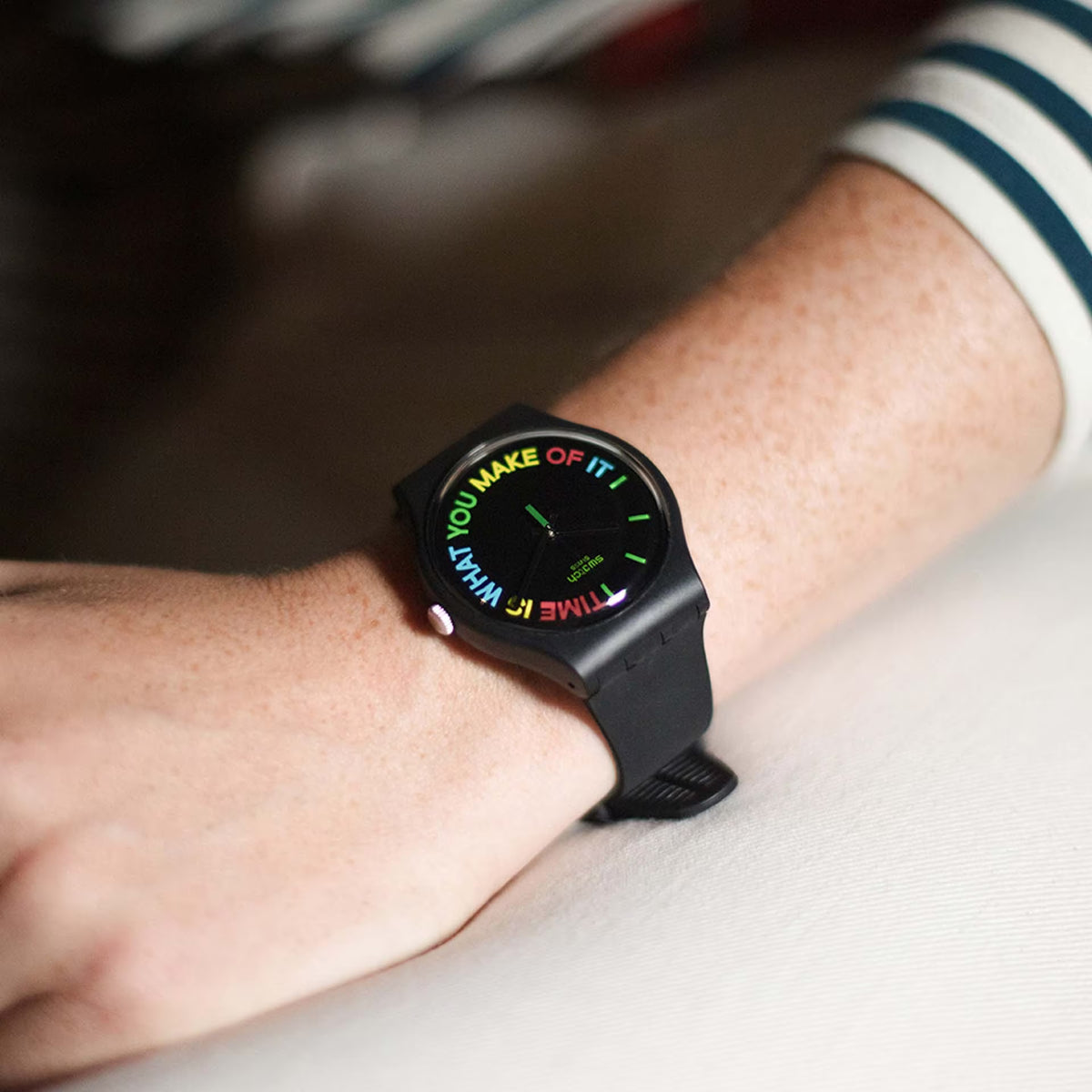 Black silicone strap wristwatch worn on wrist; black case with colorful dial text