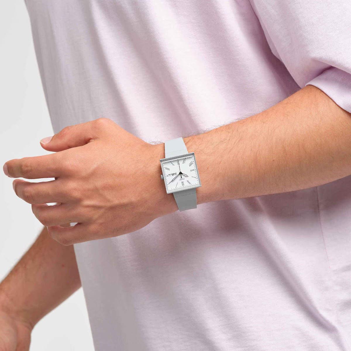 Square watch with white dial and gray strap, worn on wrist