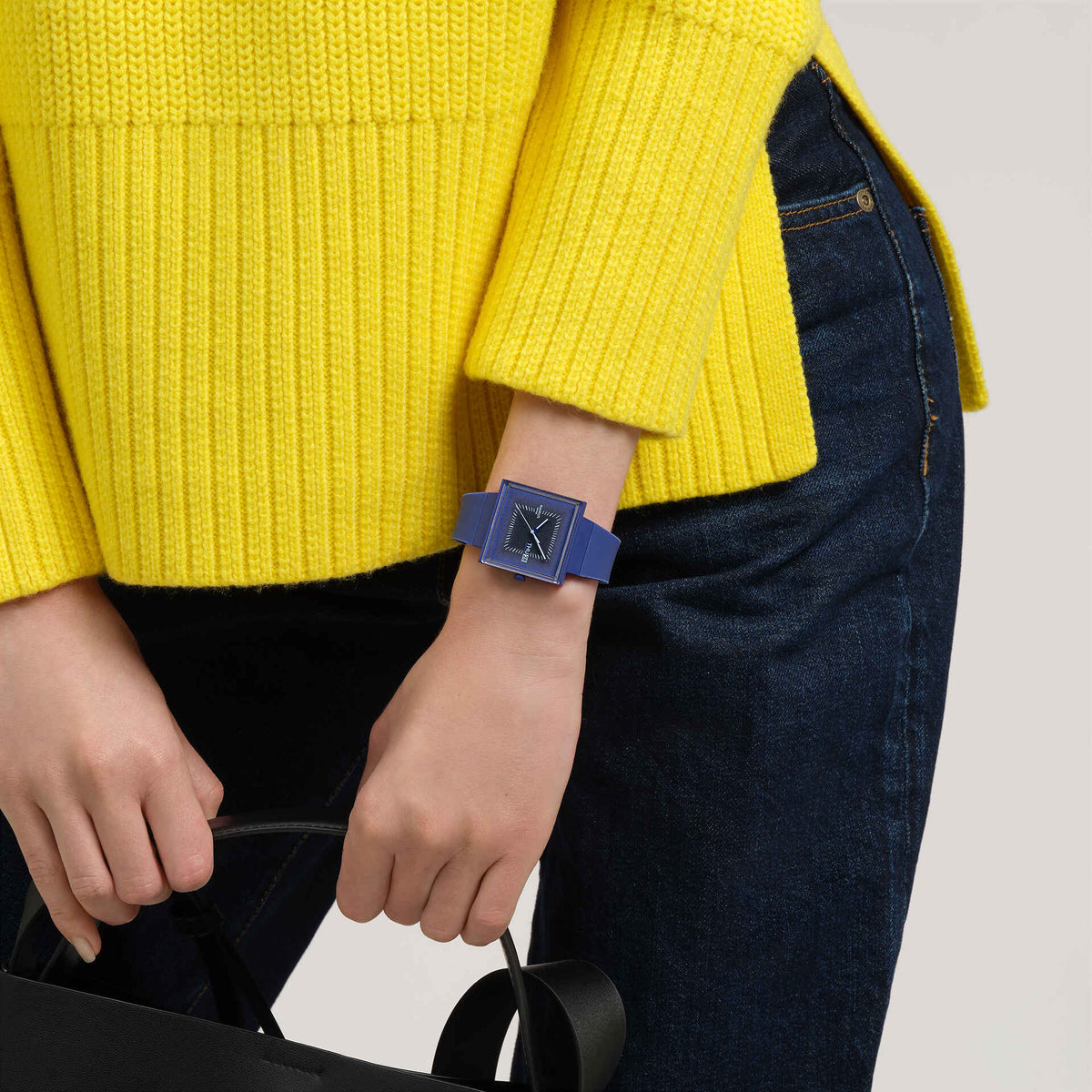 Dark blue square watch on wrist, silicone band and analog dial with THU 28