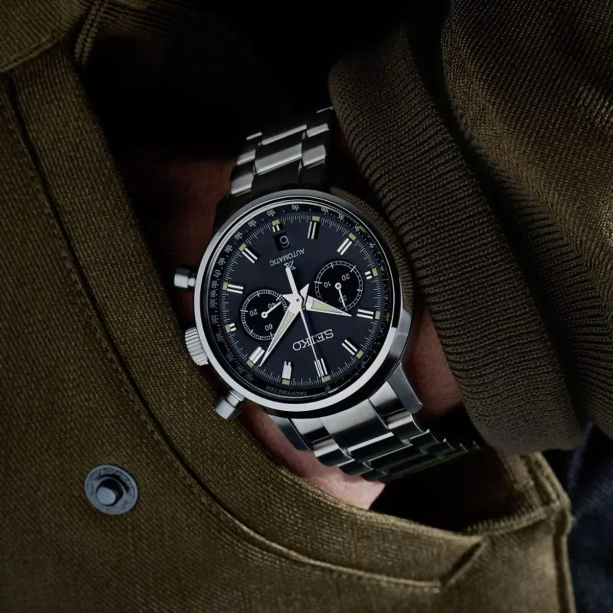 Automatic chronograph watch with black dial on stainless steel bracelet, worn on wrist