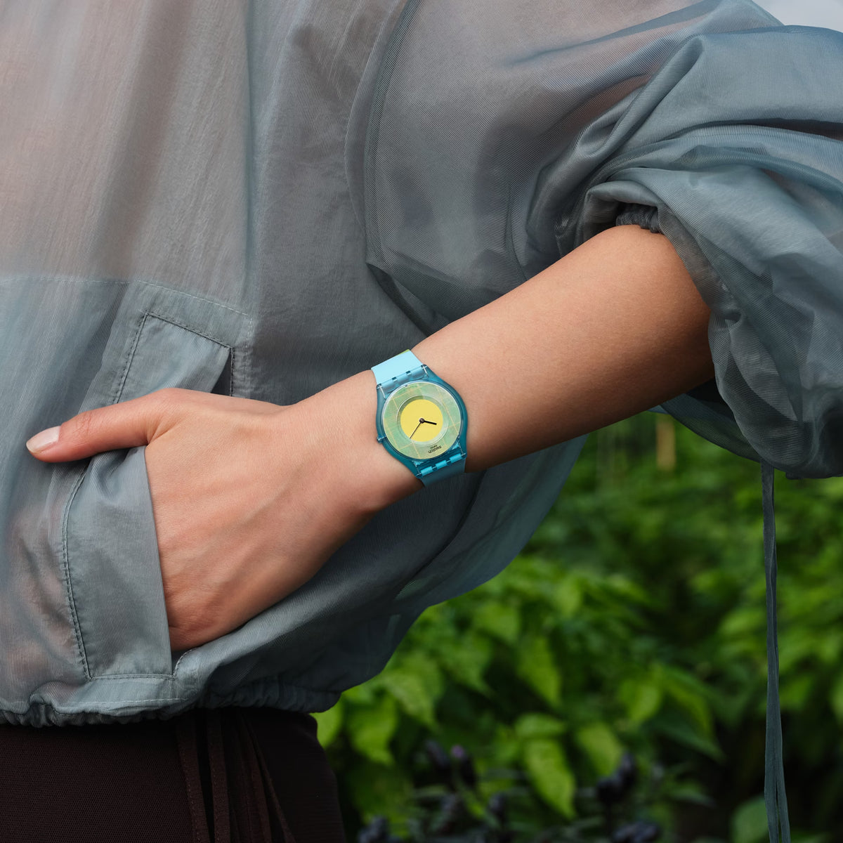 Swatch silicone strap watch on wrist, light-blue band with lime-yellow dial