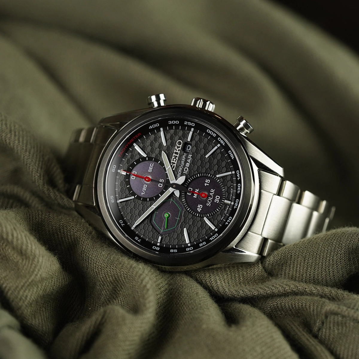 Solar chronograph wristwatch with black textured dial, steel bracelet, three subdials