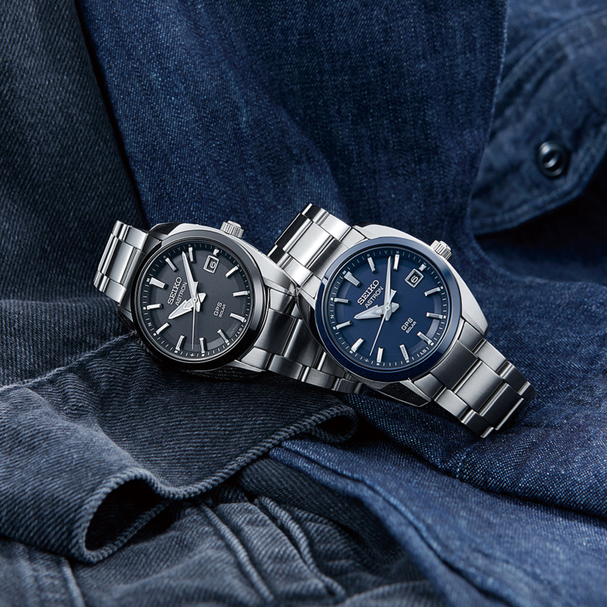 Two men's stainless steel GPS solar quartz watches with blue dials on denim