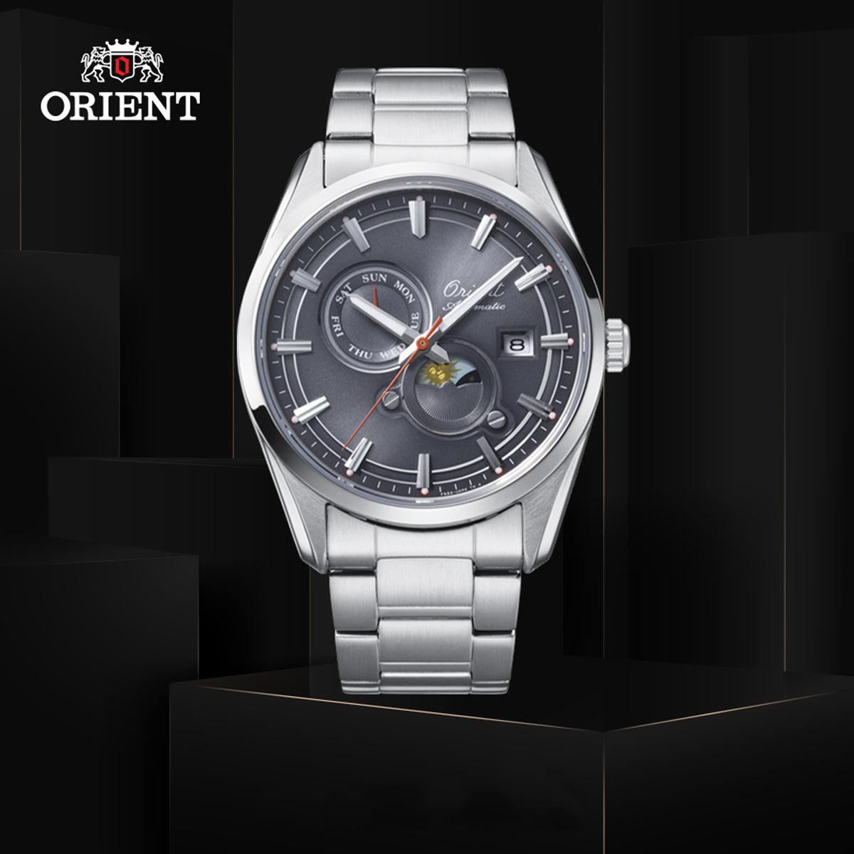 Orient Sun and Moon automatic watch with a charcoal grey dial, sub-dials, and stainless steel band displayed on dark pedestals