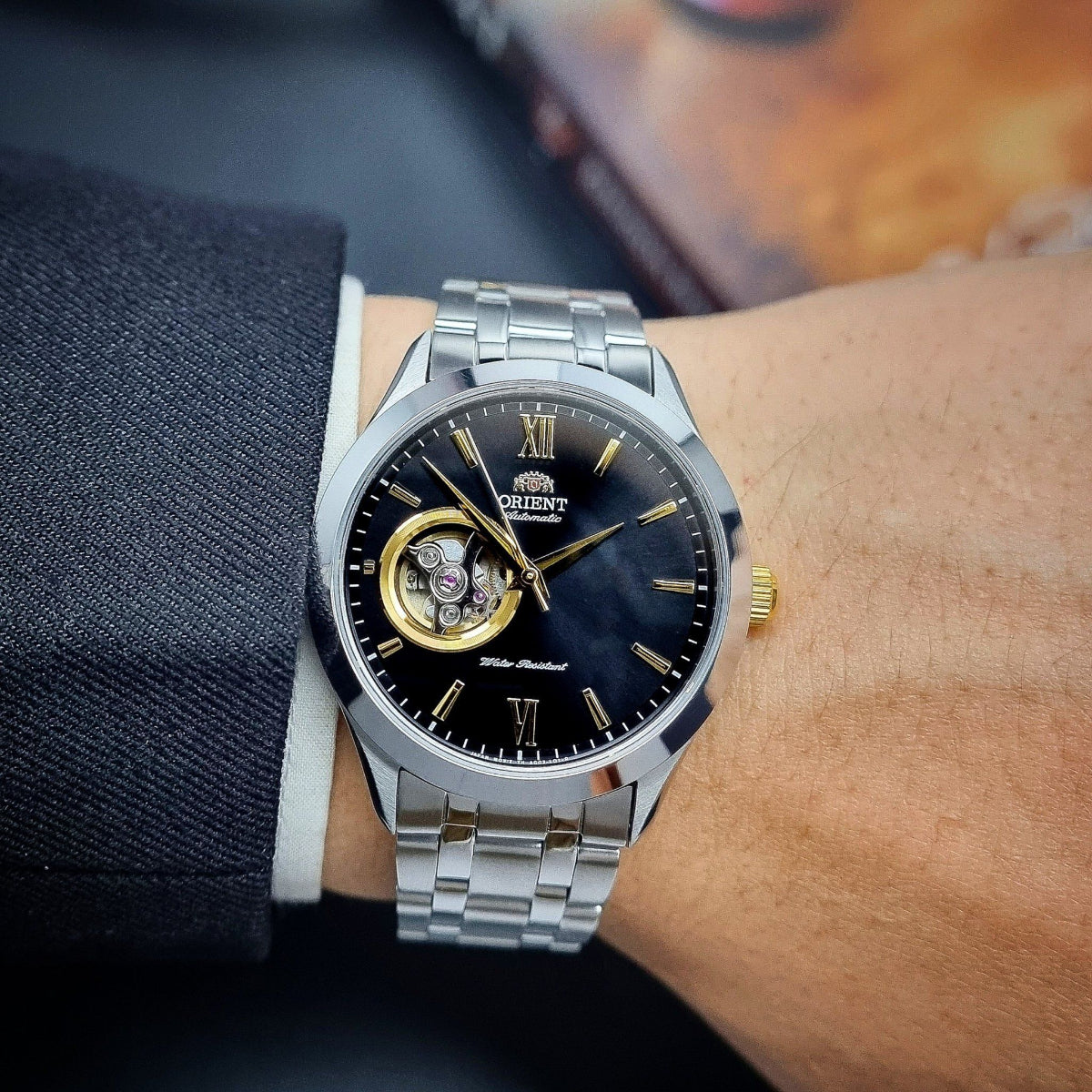 Men's automatic open-heart watch on wrist; black dial, Roman numerals, gold hands, steel bracelet