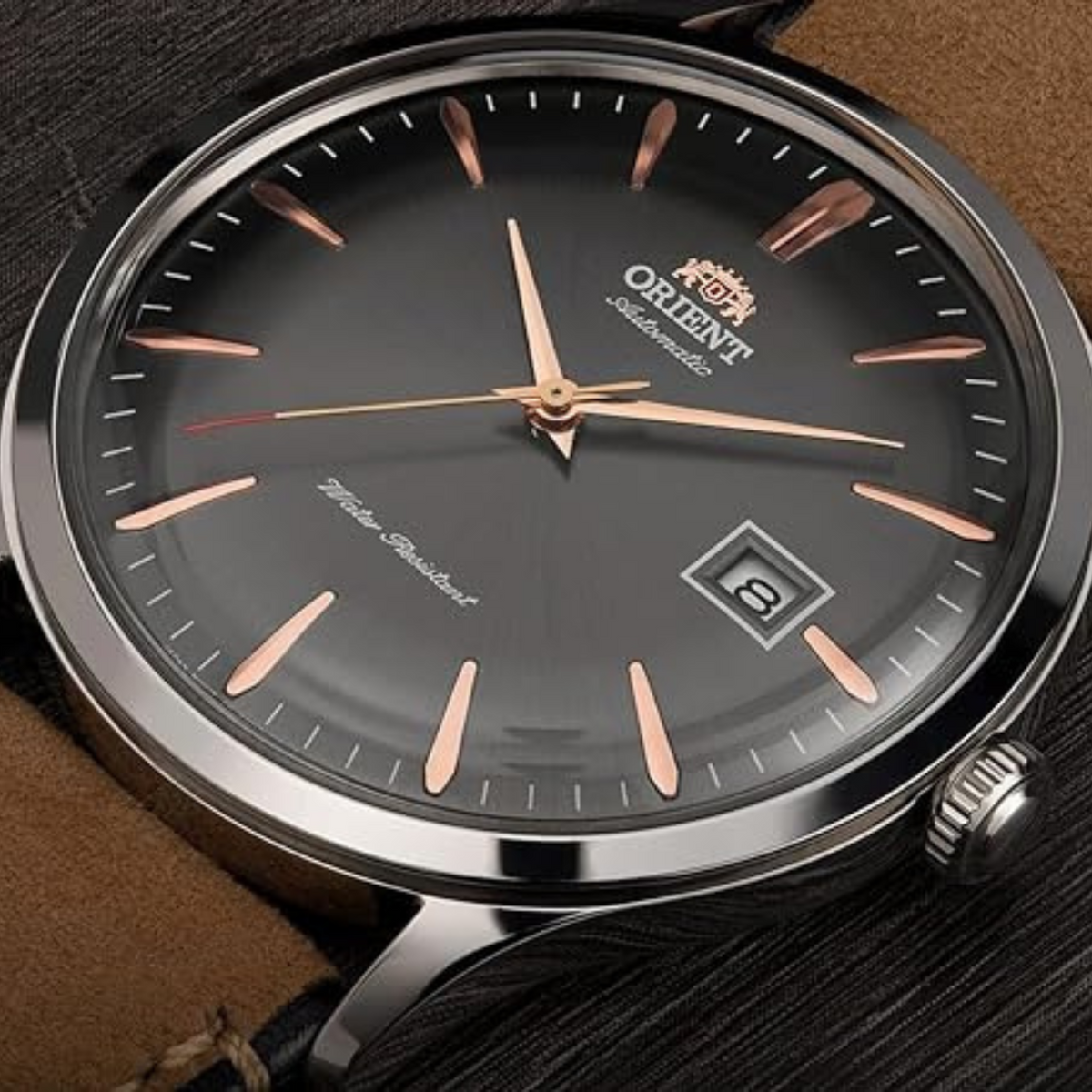Round automatic watch with dark grey dial, rose gold hands, leather strap